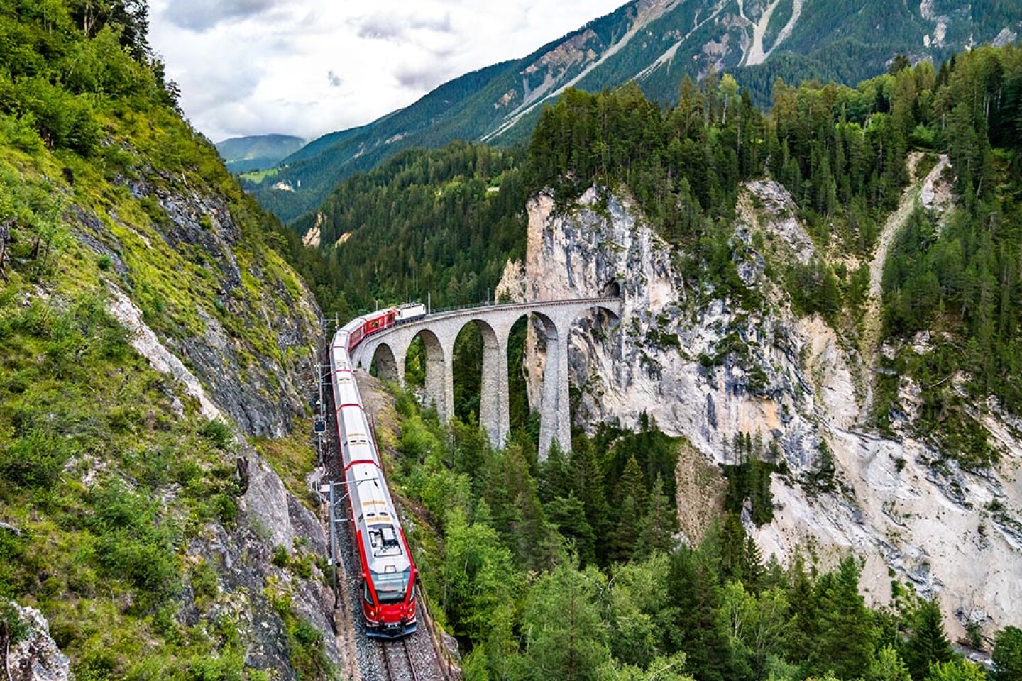 A red train traveling through mountains