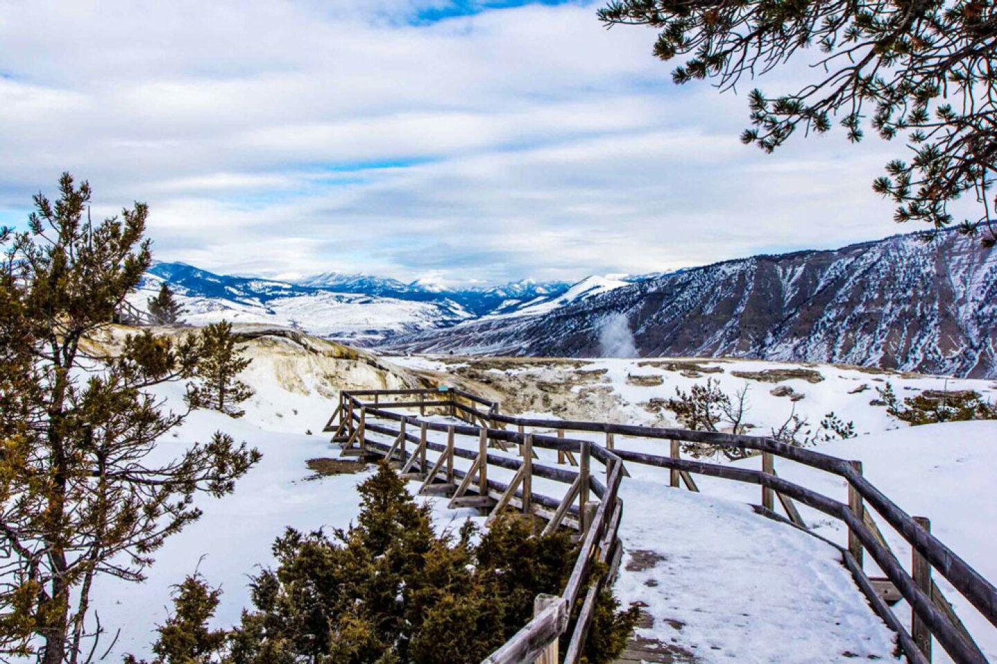 An empty walkway in Yellowstone, with snow and distant hills