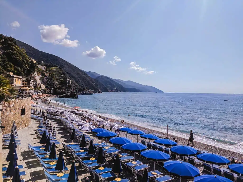 The beach with blue umbrellas and chairs at Monterosso al Mare