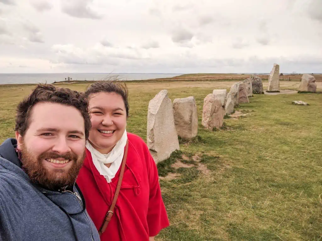 Colin and Riana taking a selfie in front of the rocks of Ales Stenar in Southern Sweden