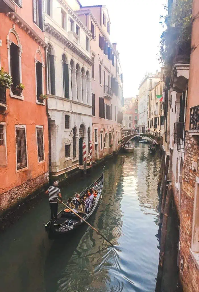 Canal in Venice with houses lining it and a gondola going past