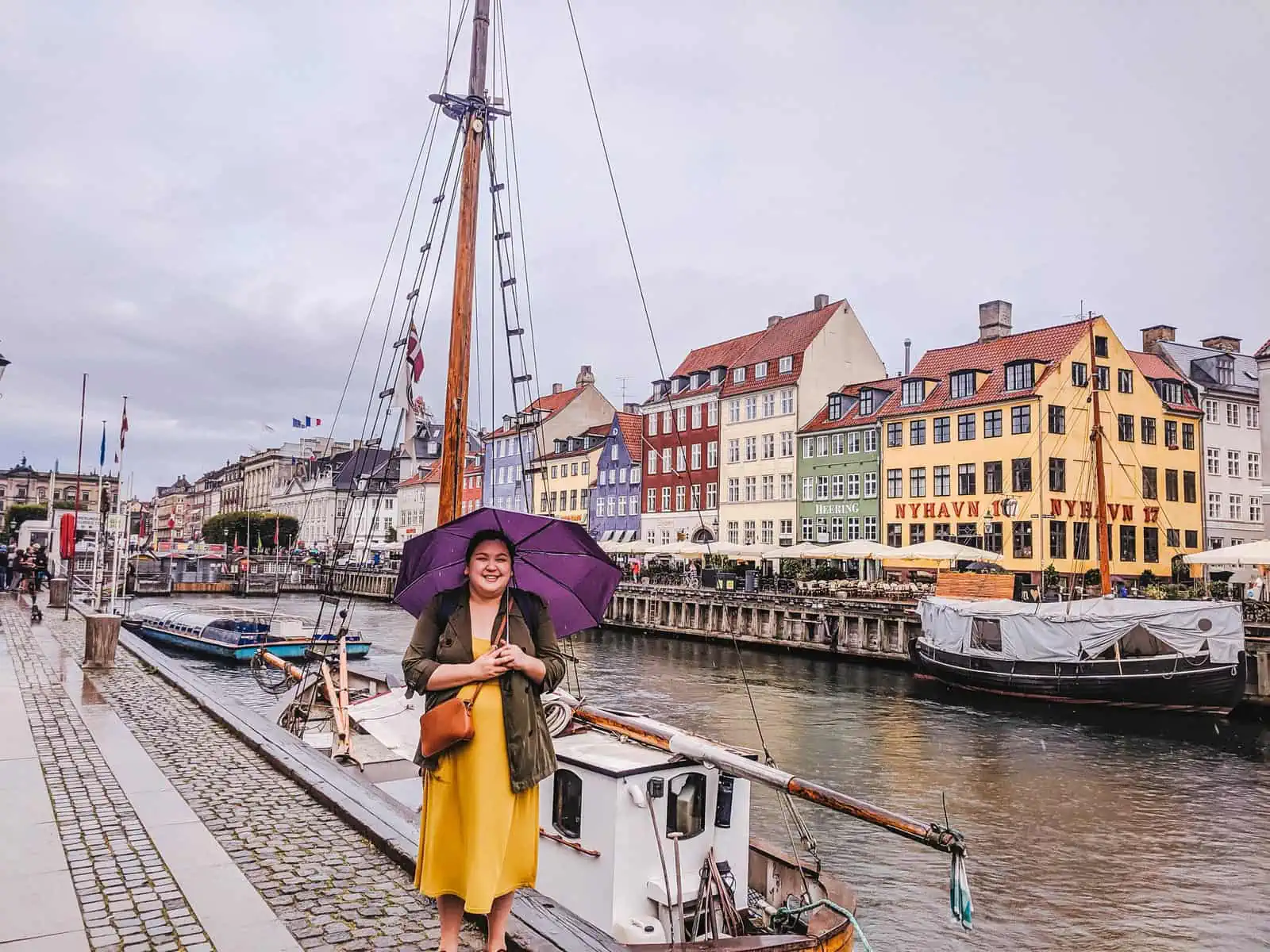 Riana standing with a purple umbrella in the rain in Nyhavn, Copenhagen!