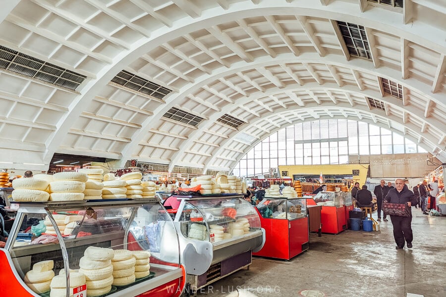Cheese for sale inside Kutaisi Green Bazaar, a huge market with a curved white ceiling.