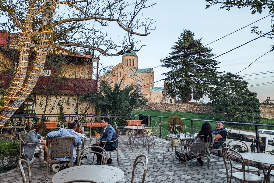 People sit on the terrace of cafe in Kutaisi with a view of Bagrati Cathedral.