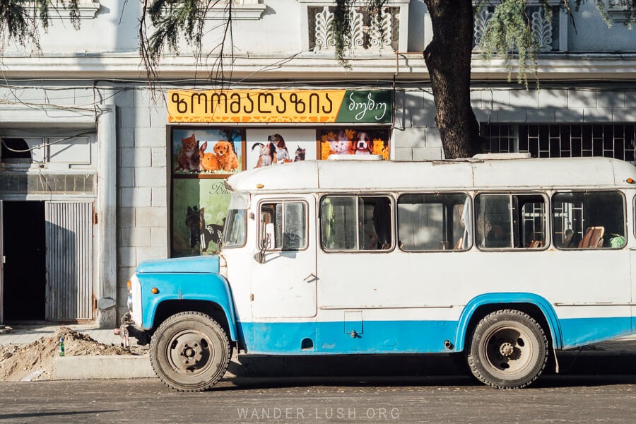 An old blue and white bus on a street in Kutaisi.