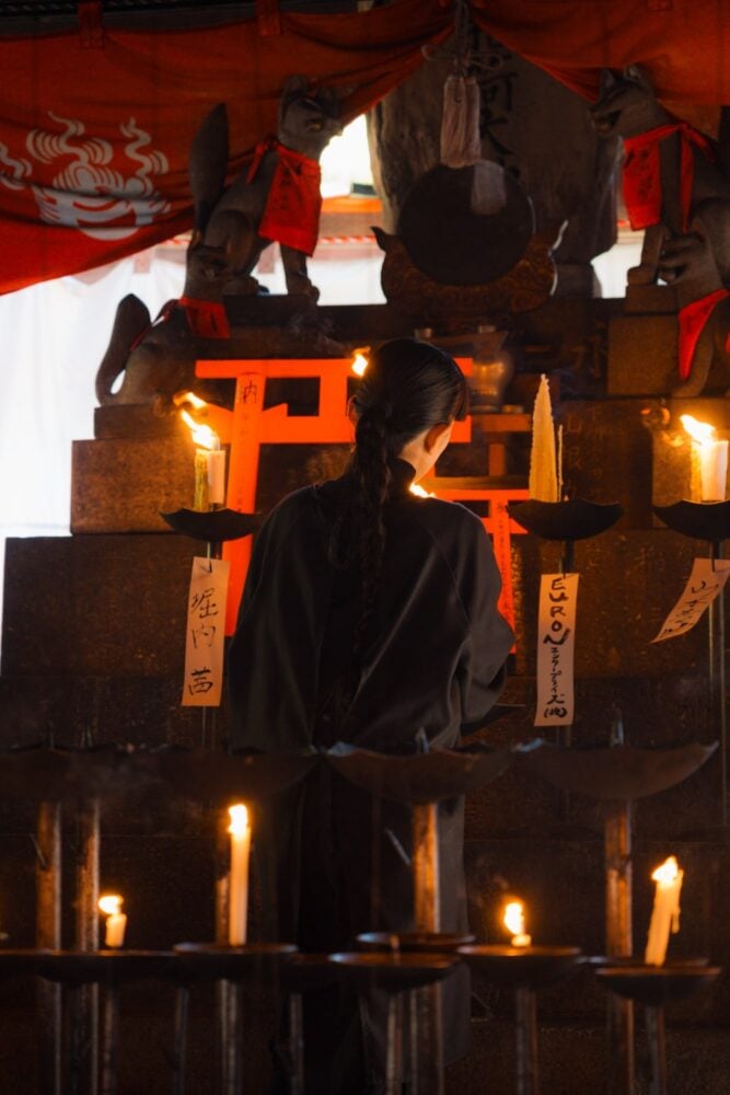 A woman lighting candles at the Fushimi Inari shrine altar in Kyoto, Japan.