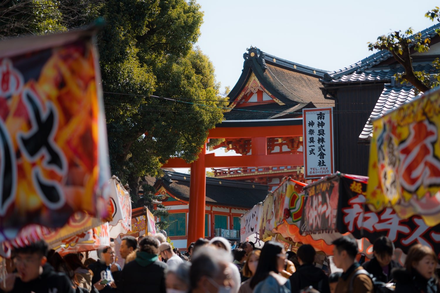 Tourists at Fushimi Inari Shrine west entrance with street food stalls.