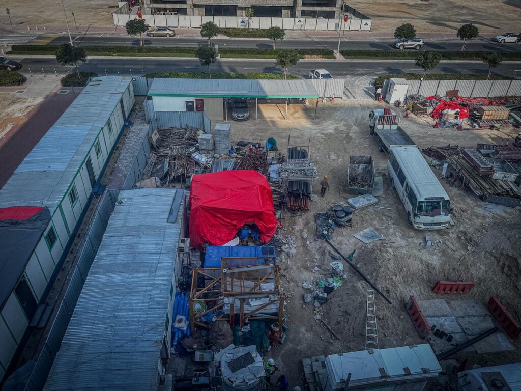 Aerial view of Dubai construction site with workers, materials, and equipment.