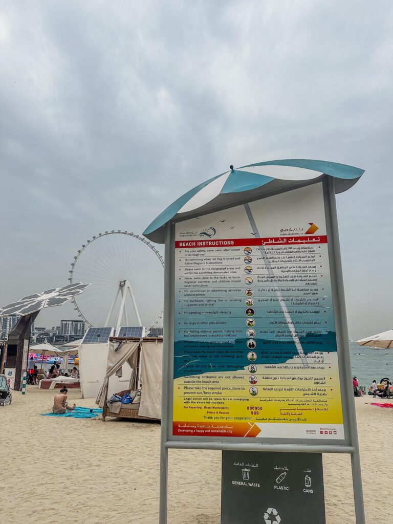 Jumeirah Beach, Dubai: Beachgoers, Ain Dubai Ferris wheel, multilingual beach instructions