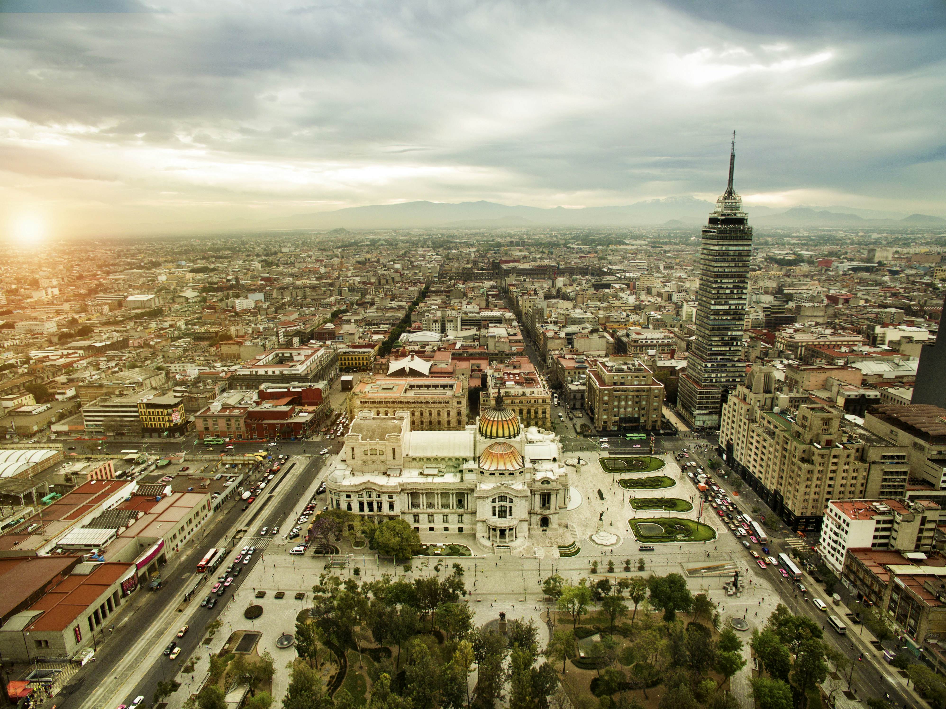 Aerial view of the Mexico City's grid layout, with a white domed building in the foreground, and a taller structure to the right 