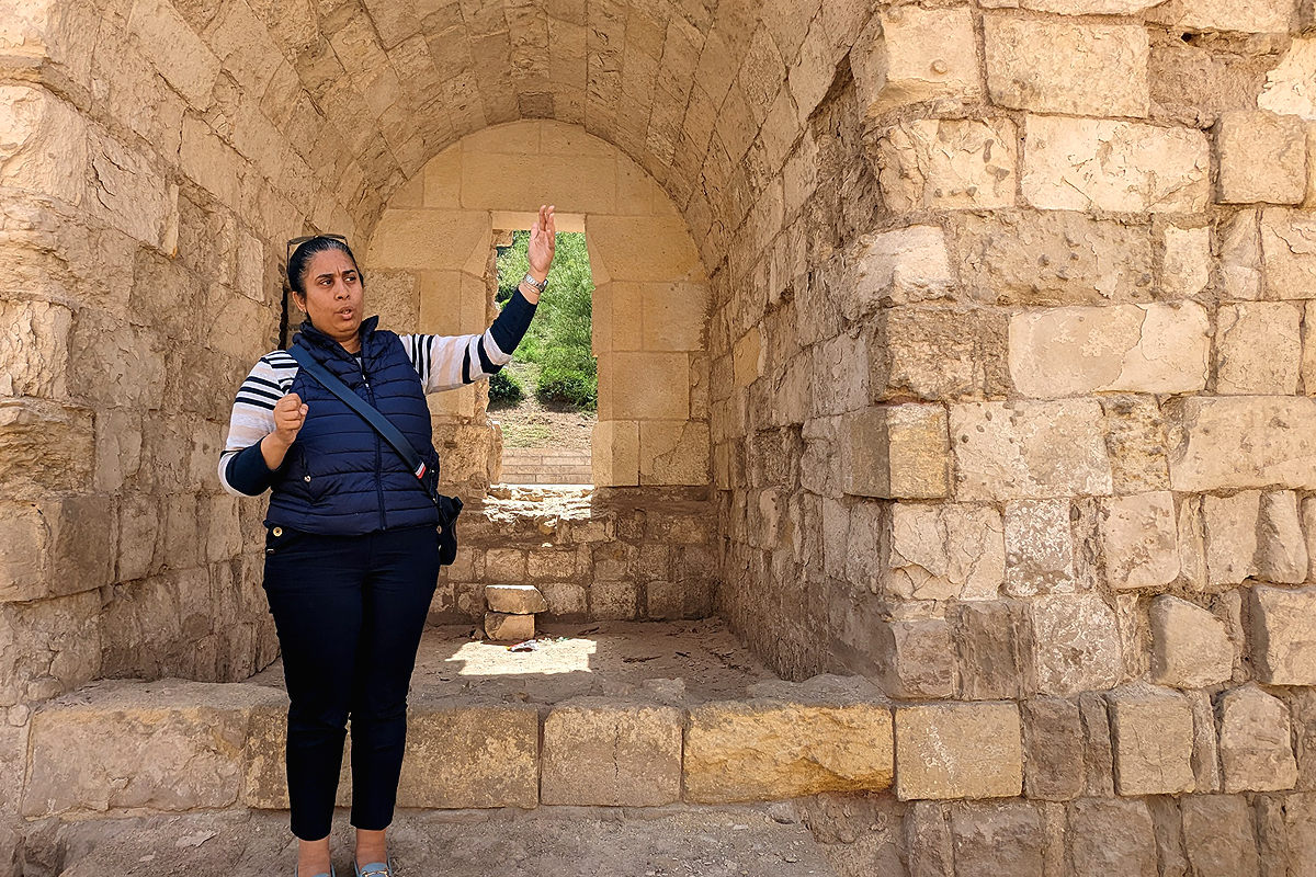 A tour guide stands at the Ayyubid Wall in Cairo's Azhar Park explaining the wall's history.