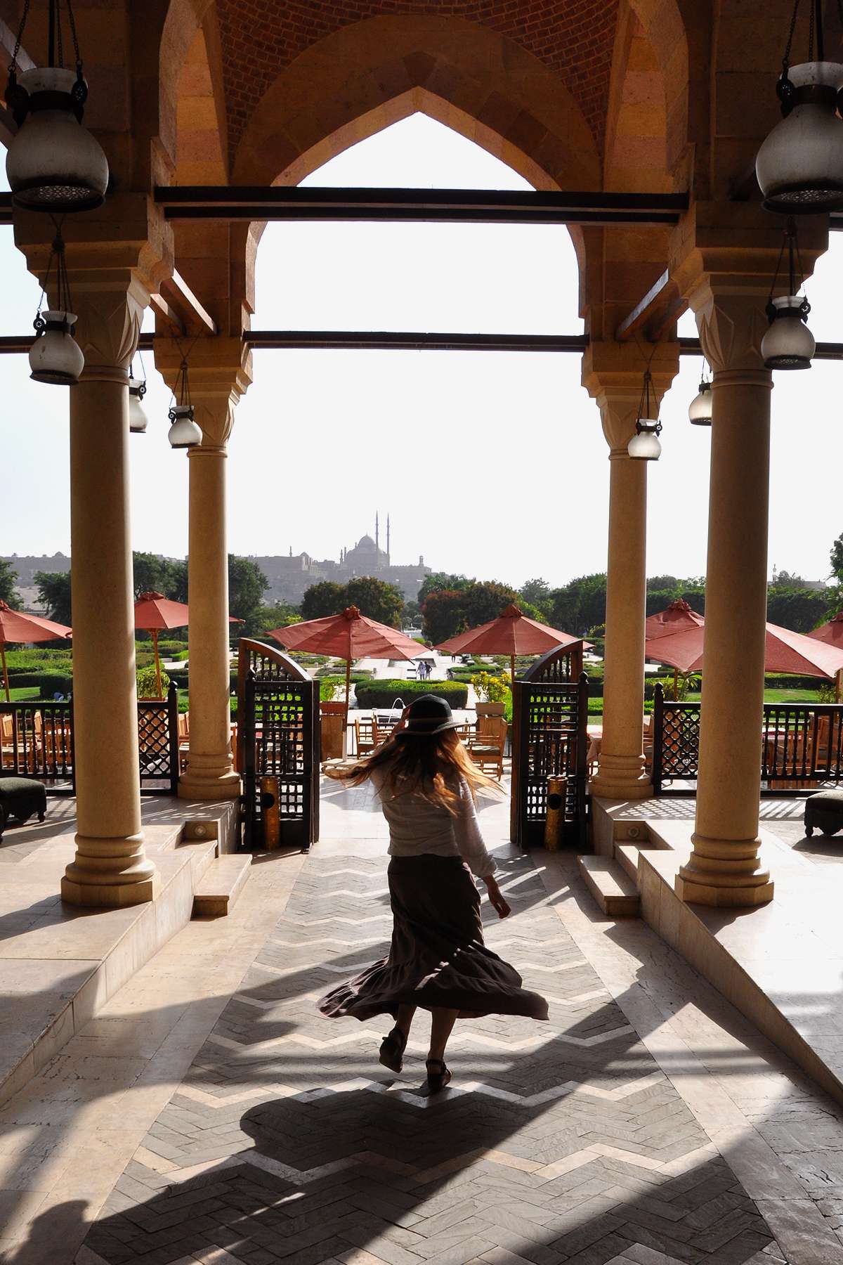 Dee twirls in a long skirt at Azhar Park amid the columns of the Studio Masr Restaurant. 