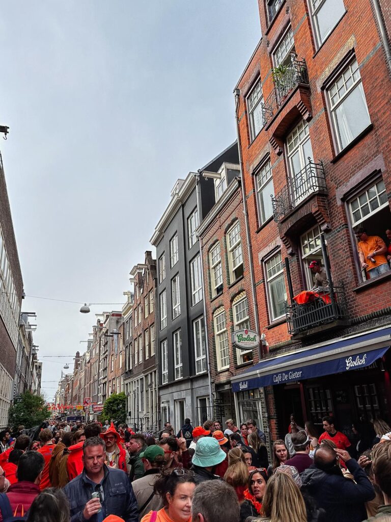 King's Day Street Party in Amsterdam, filled with orange-clad partygoers and iconic Dutch architecture.