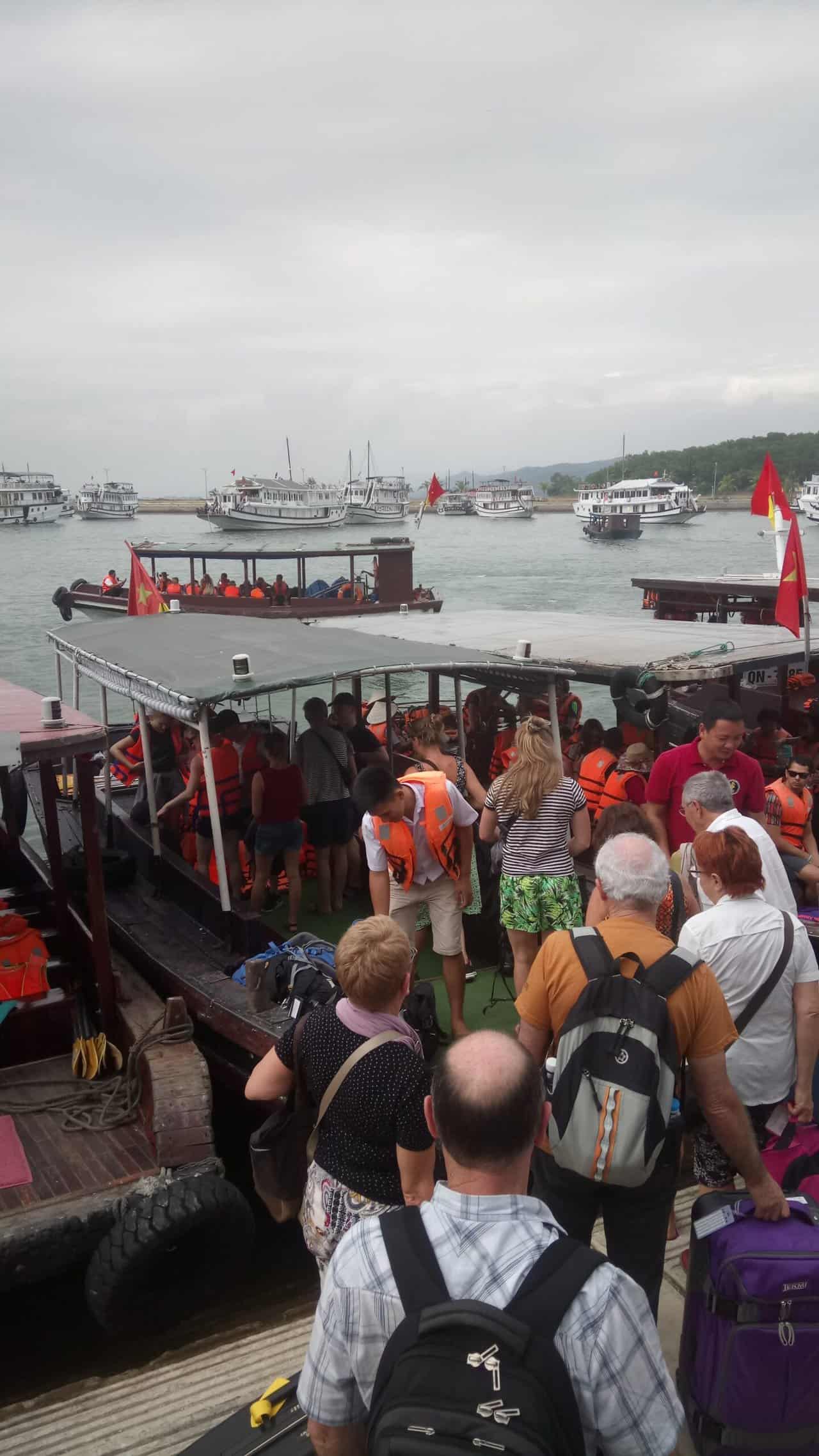 Travellers getting on small boats at Halong Marina to take them out to their cruise boats 