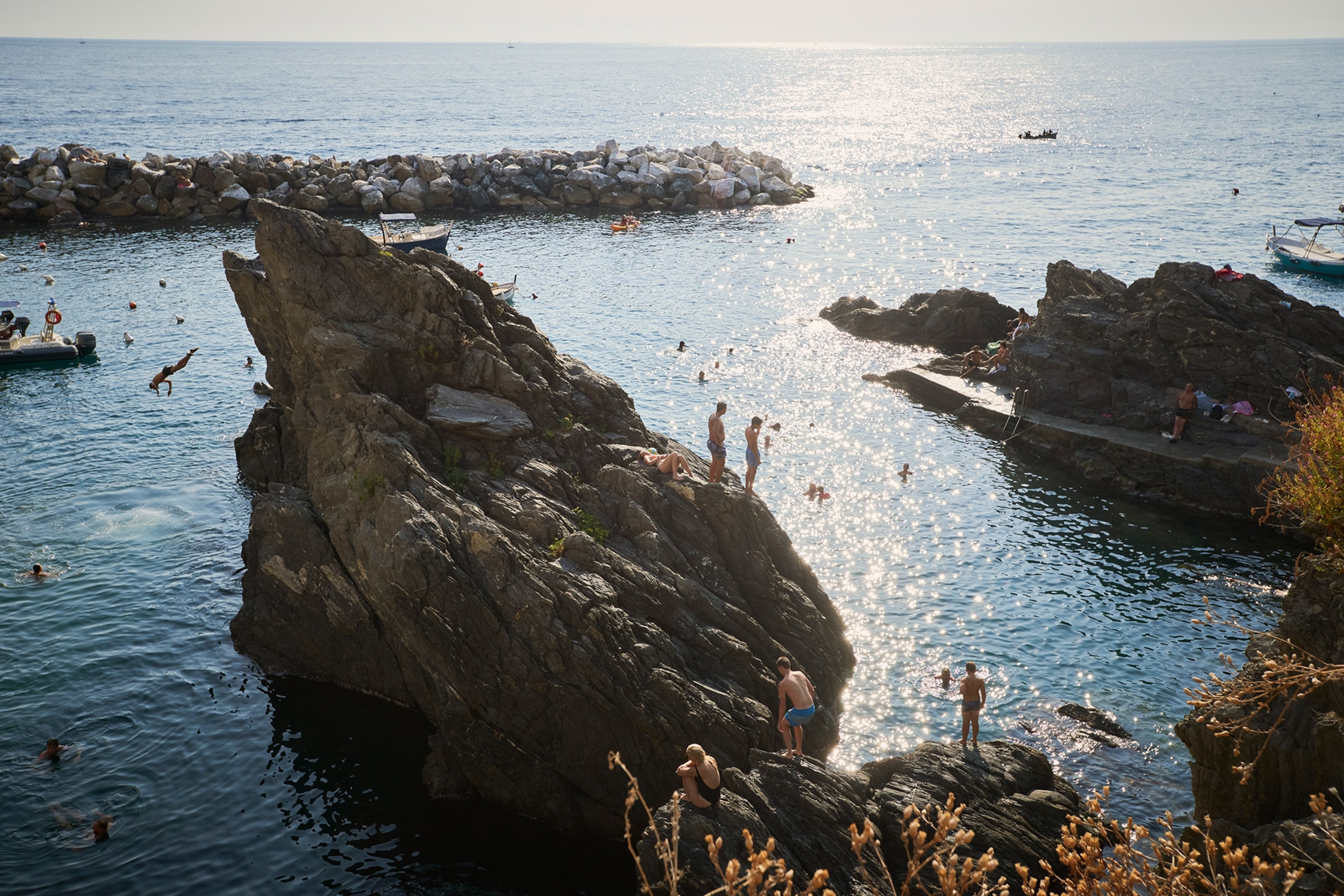 People swim and dive from the large rocks jutting from the ocean