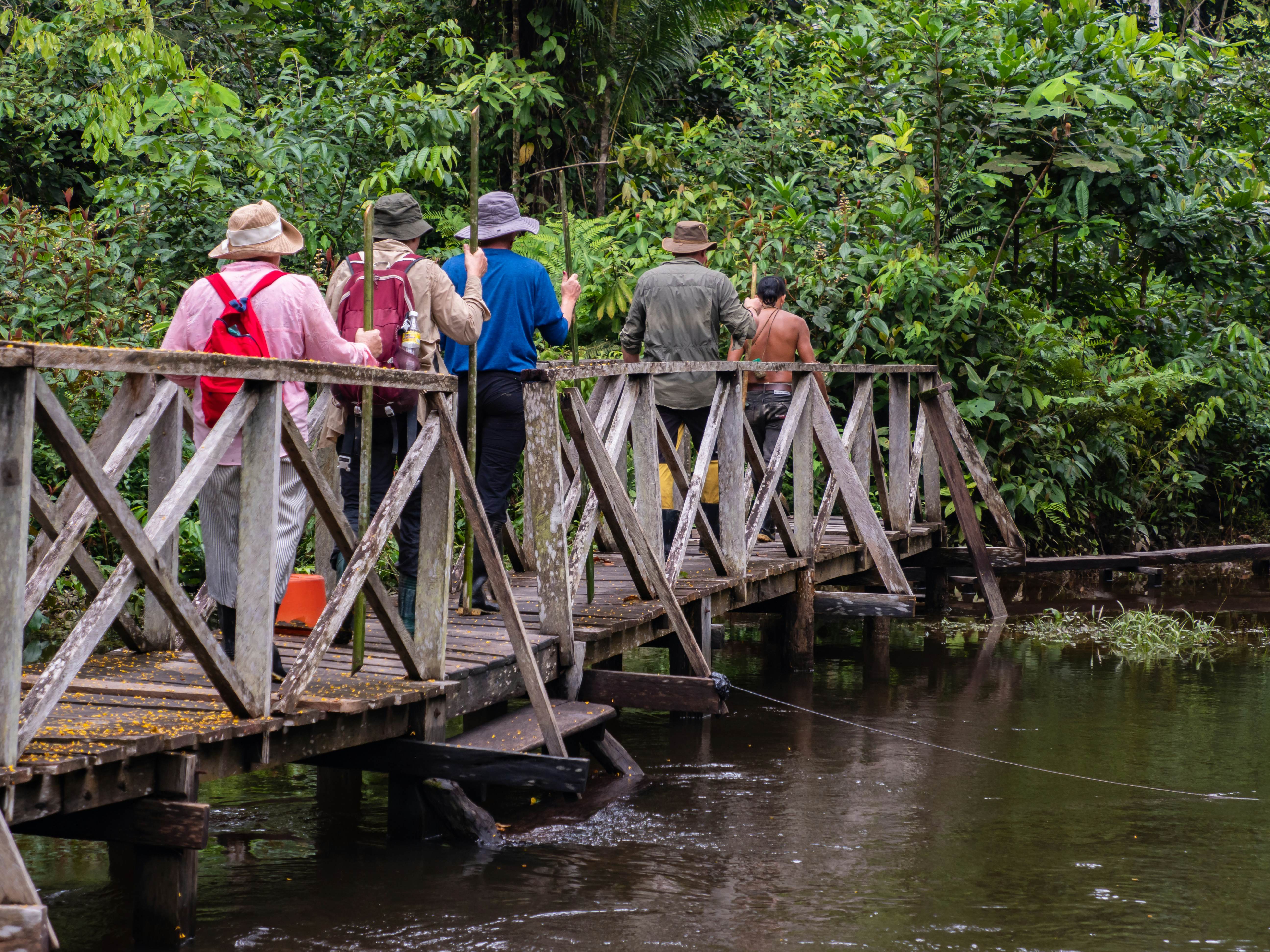 A group of people walk over a wooden bridge in the Colombian Amazon