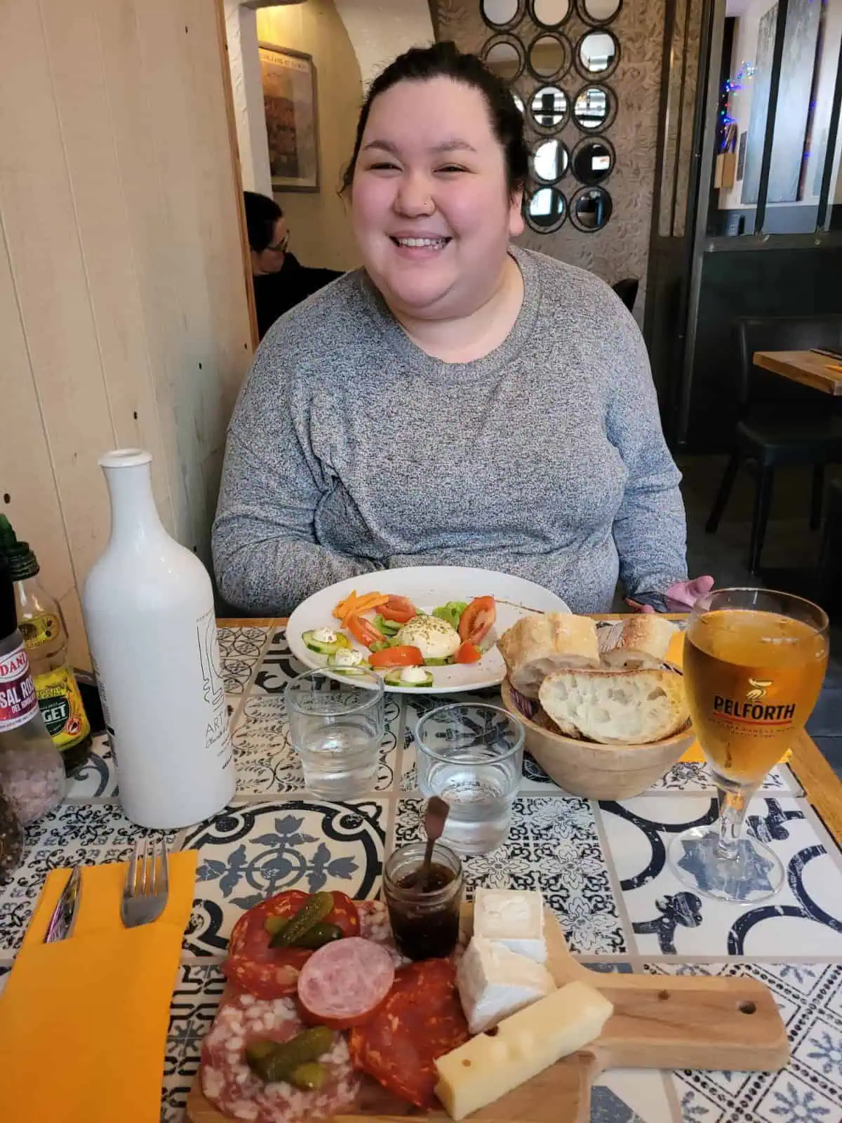 Riana eating lunch in Carcassonne at a small restaurant. In front of her there is a salad and bowl of bread. 