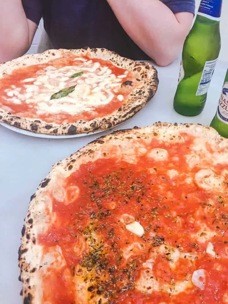 Two large pizzas and two beers on a table in Naples, Italy