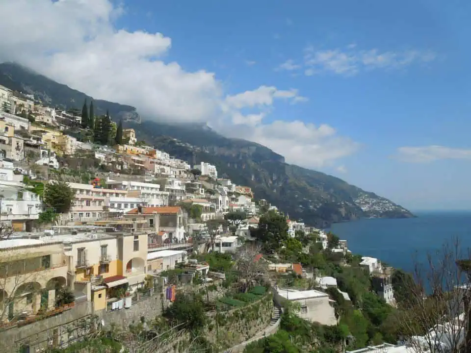 View of Positano, Italy from the cliff with buildings sloping down the mountain and the sea off the coast