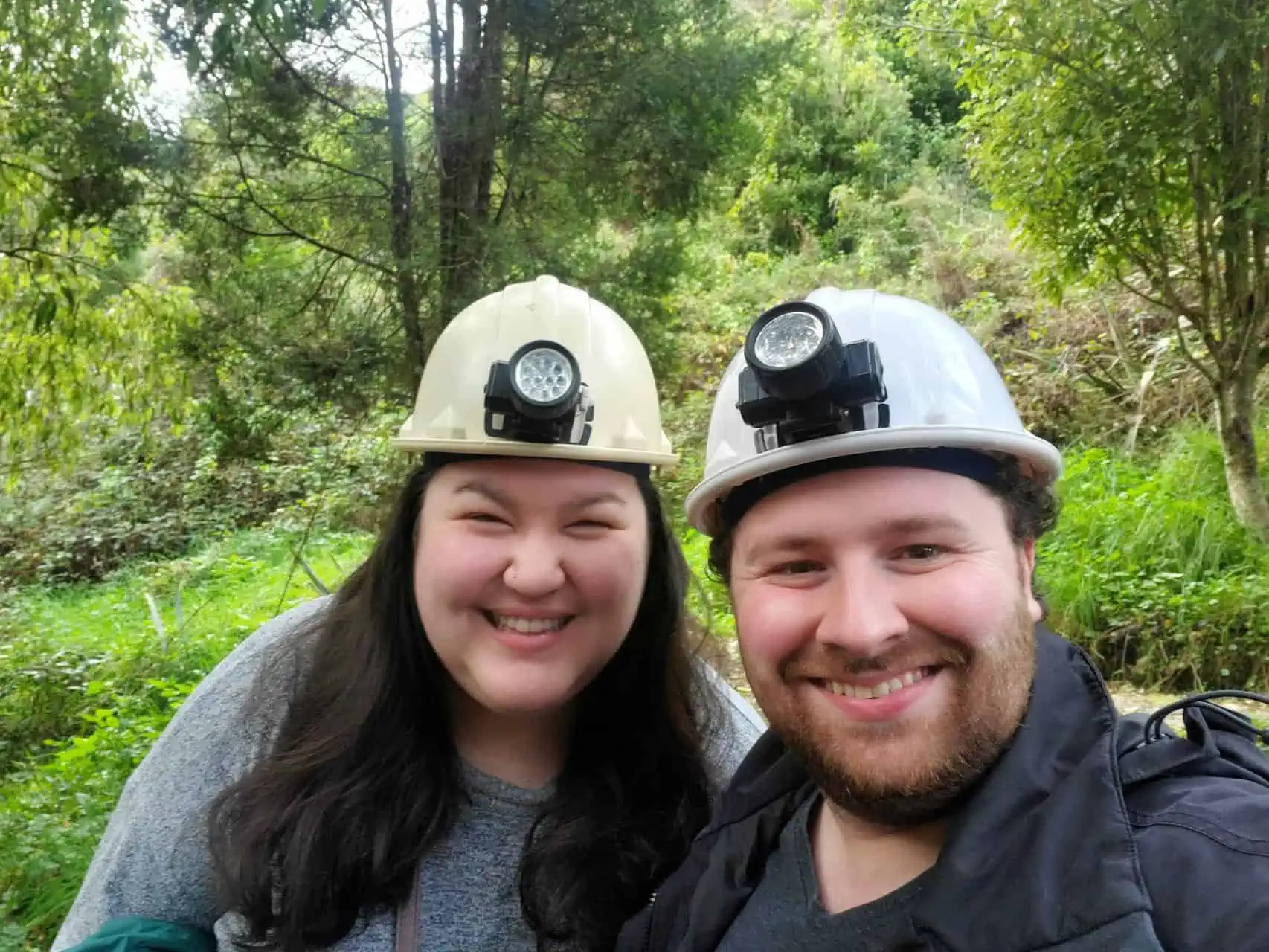 Riana and Colin wearing hard hats with lights about to go into glowworm caves in Waitomo, New Zealand