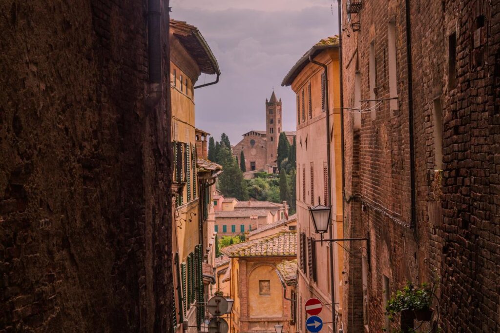 Siena alleyway with terracotta roofs and view of Basilica Catarina
