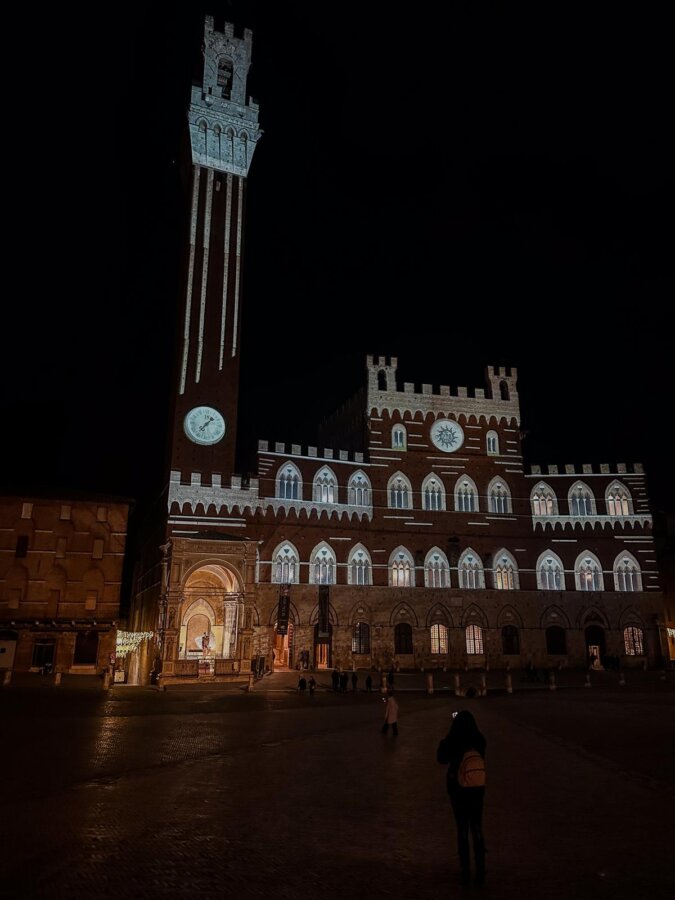 Christmas evening in Siena's Piazza del Campo with festive lights and Torre del Mangia