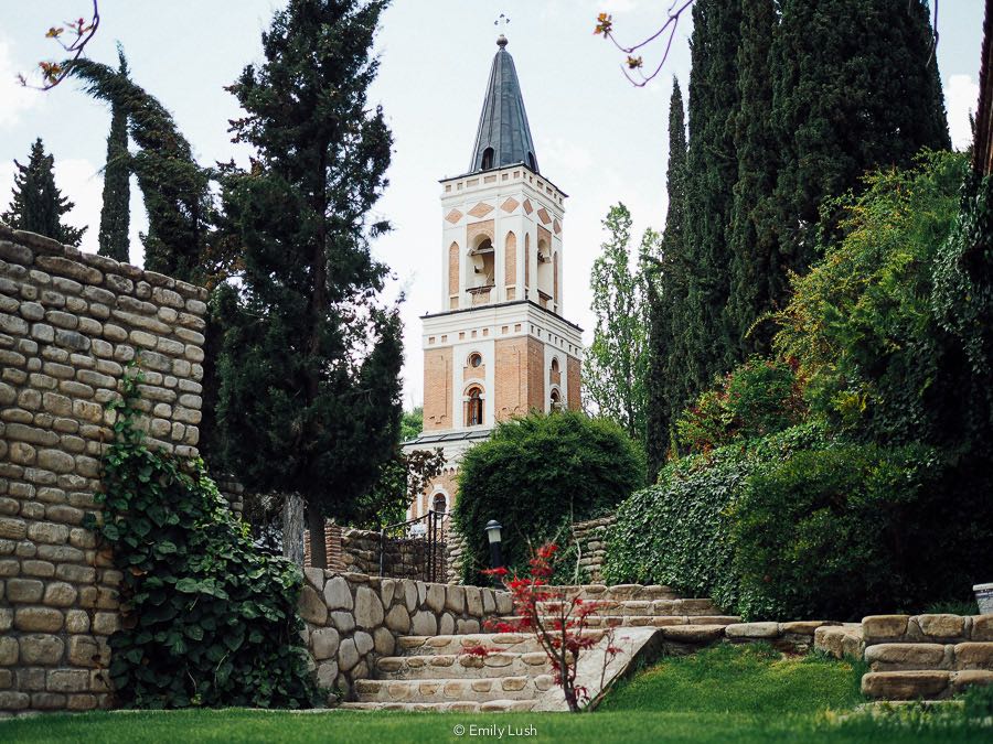 A pink church tower surrounded by greenery.