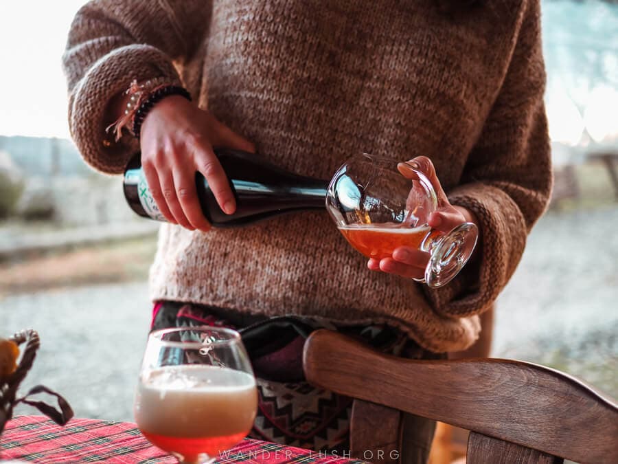 A woman in a jumper pouring craft beer into a glass at Lost Ridge Inn near Sighnaghi.
