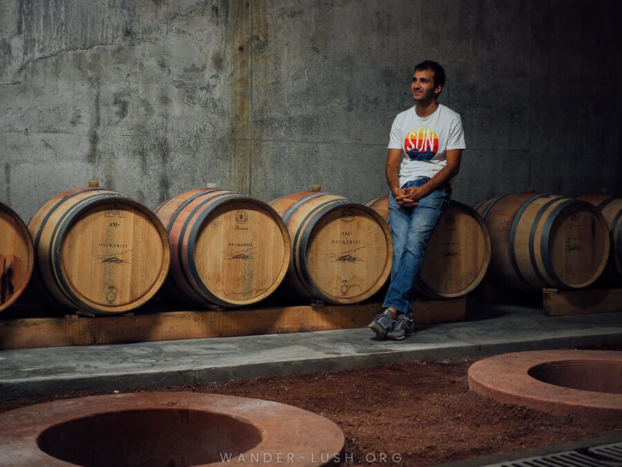 A man leans against oak barrels at a winery in Kakheti.