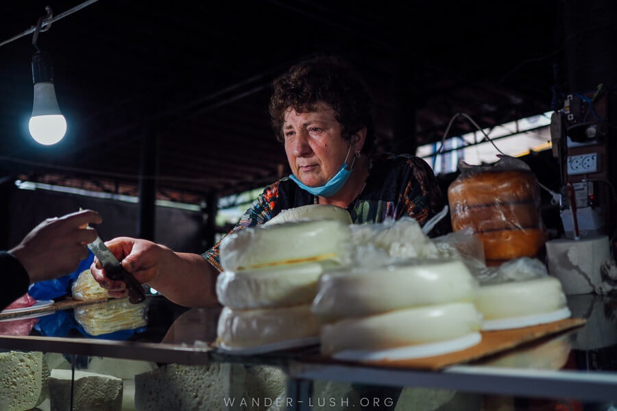 A woman hands a person a piece of farm fresh cheese inside the Telavi Bazaar in Kakheti.