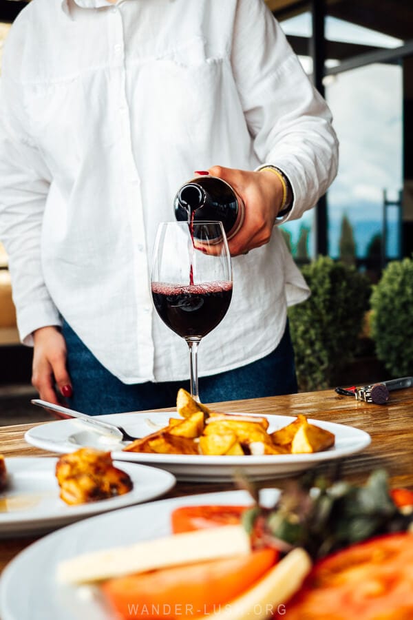 A woman pouring red wine into a glass at a winery in Kakheti.