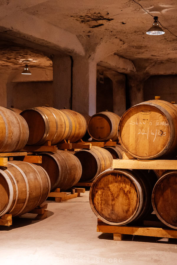 Oak barrels on wooden stands in the underground spirit reserve at Bolero Winery in Georgia.