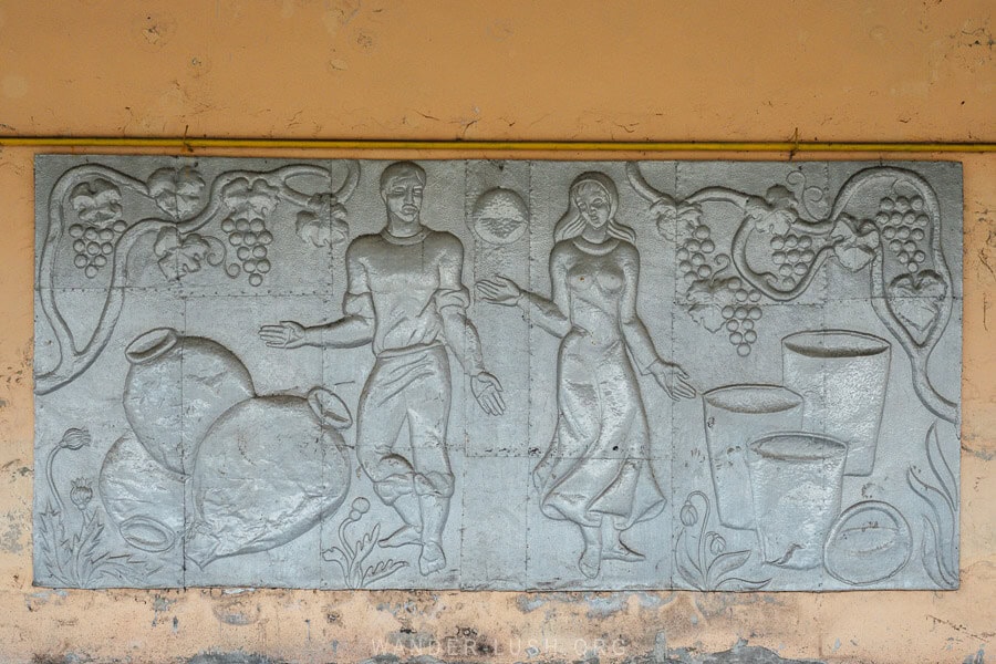 A Soviet panel sculpture showing a man and a woman making wine, hanging on a train platform in Kakheti, Georgia.