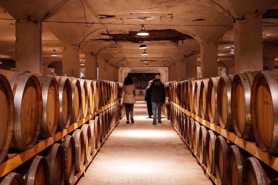 Three people walk through the underground Spirit Reserve at a wine factory in Georgia.