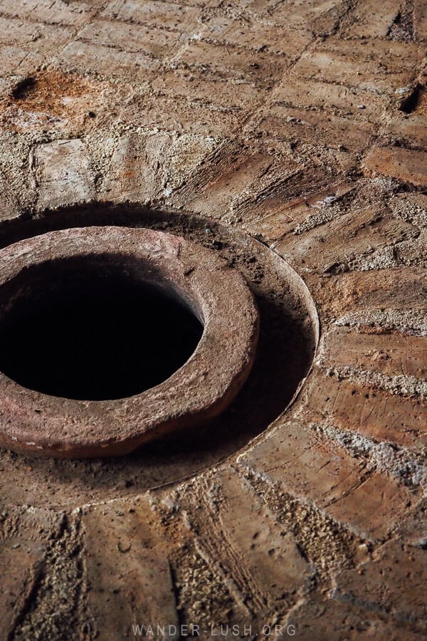 A round hole in the ground opens up to a clay qvevri, used for making Georgian wine.