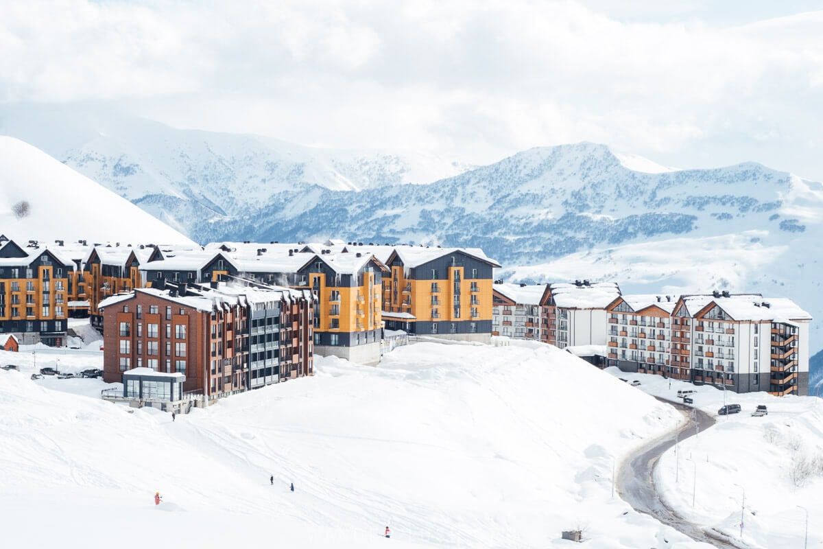 Modern loft buildings set against a backdrop of snowy mountains in the ski resort village of Gudauri in Georgia.