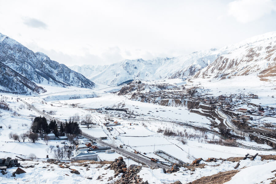 A snowy mountainscape with a road cutting through it outside Gudauri in Georgia.