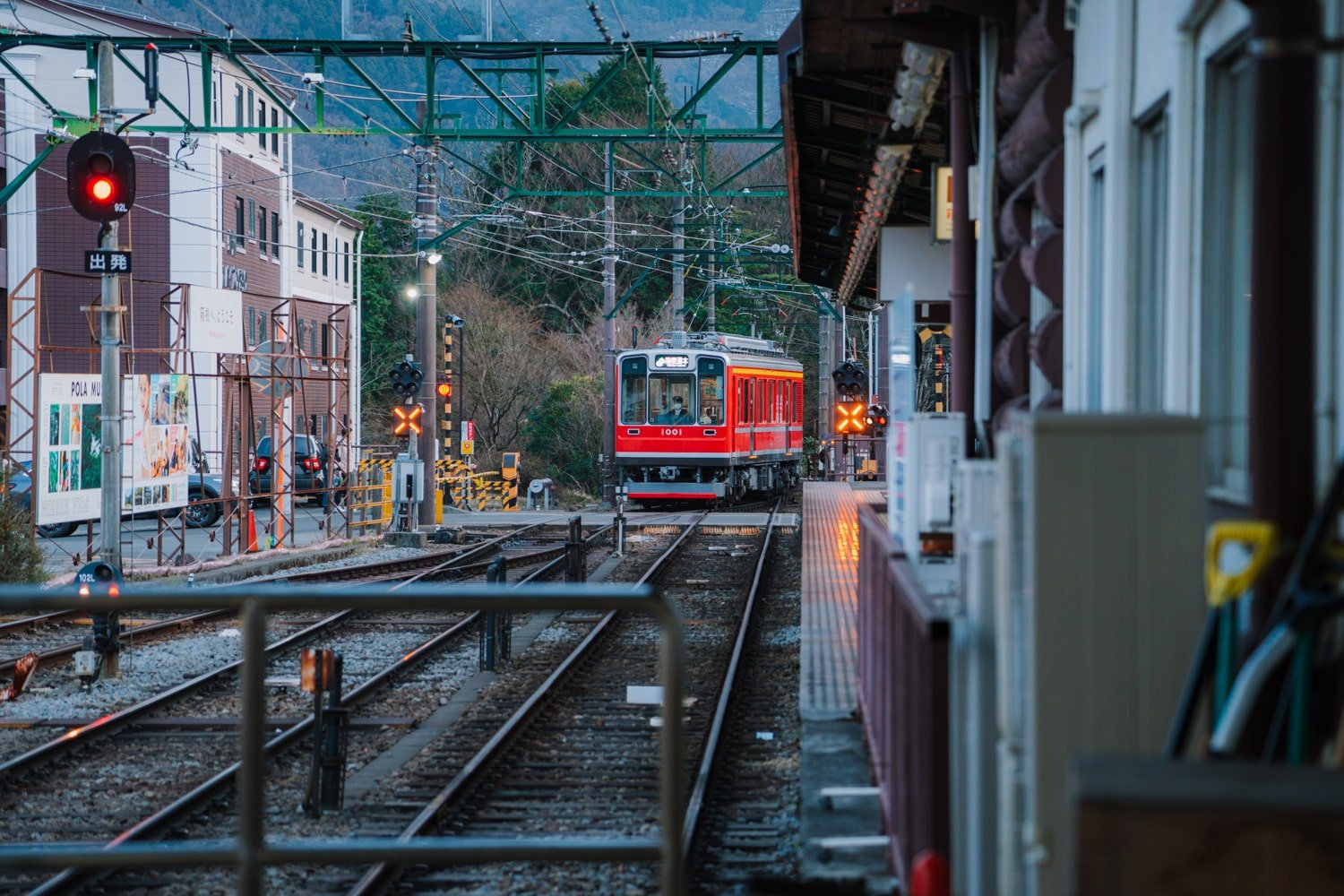 A red passenger train (Hakone Tozan line) on railway tracks arriving at the Gora station in Hakone, Japan.