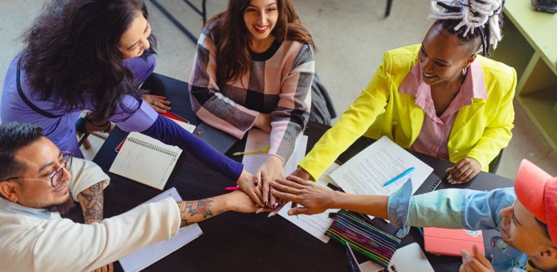 networking event, group of people gathered around a table with hands in centre, brainstorming