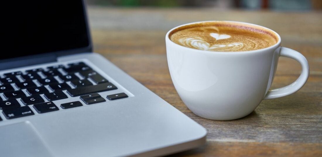 laptop and coffee on desk, latte art in cup