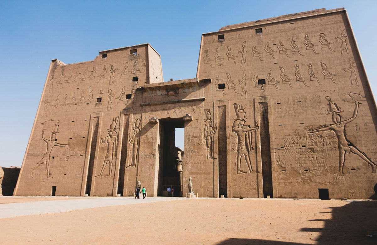 A grand pylon stands at the entrance of the Edfu temple in Egypt lined with statues of the falcon god Horus.