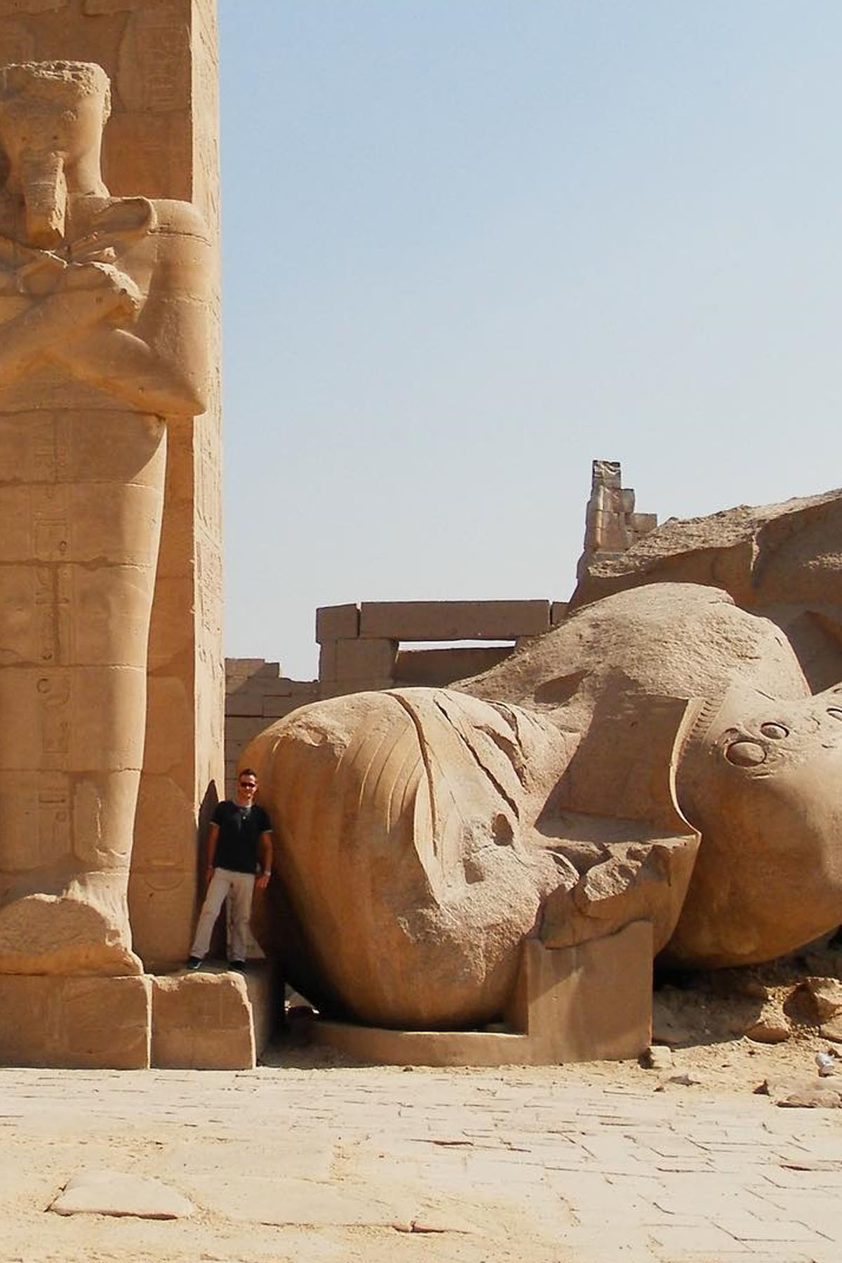 The enormous colossus at the ramasseum in luxor lays on the ground next to an upstanding statue. 