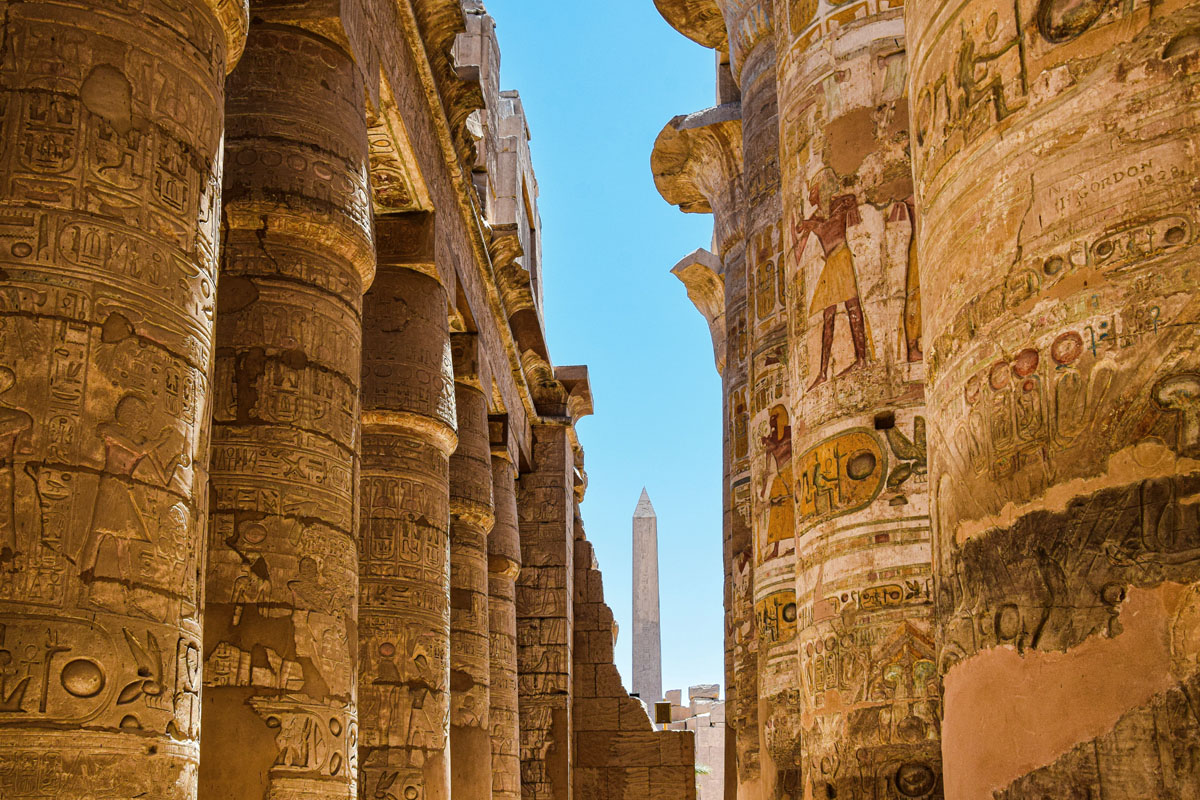 Rows of columns with an obelisk in the background at Karnak Temple in Luxor.