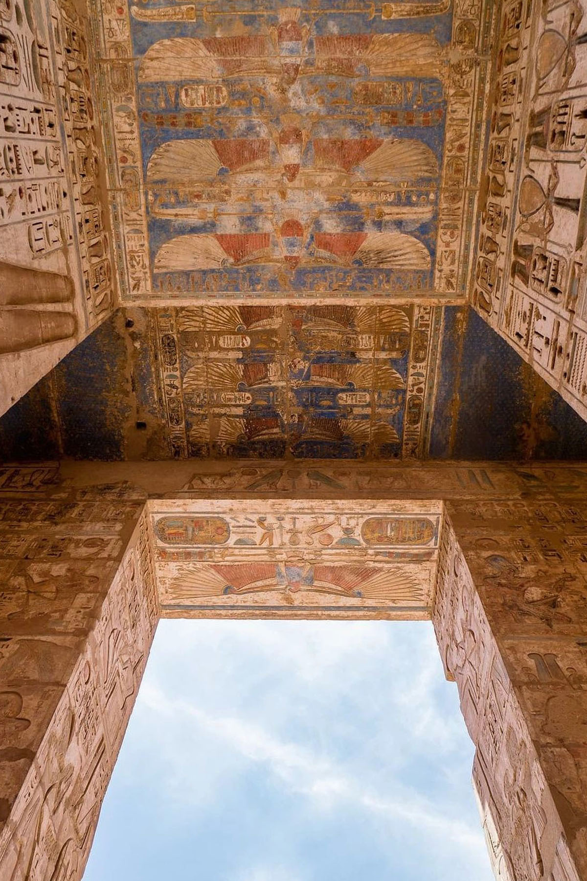 A gateway at the Medinet Habu temple in Luxor shows colorful reliefs in oranges and blues. 