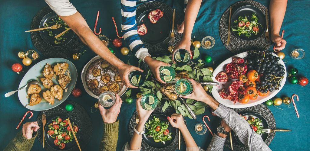 Group of people gathering over food, cheers over drinks