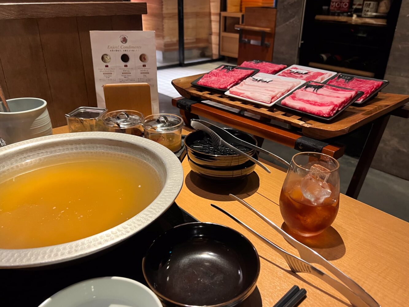 Japanese Shabu-Shabu with a large bowl of hot broth and tray of thinly sliced beef.