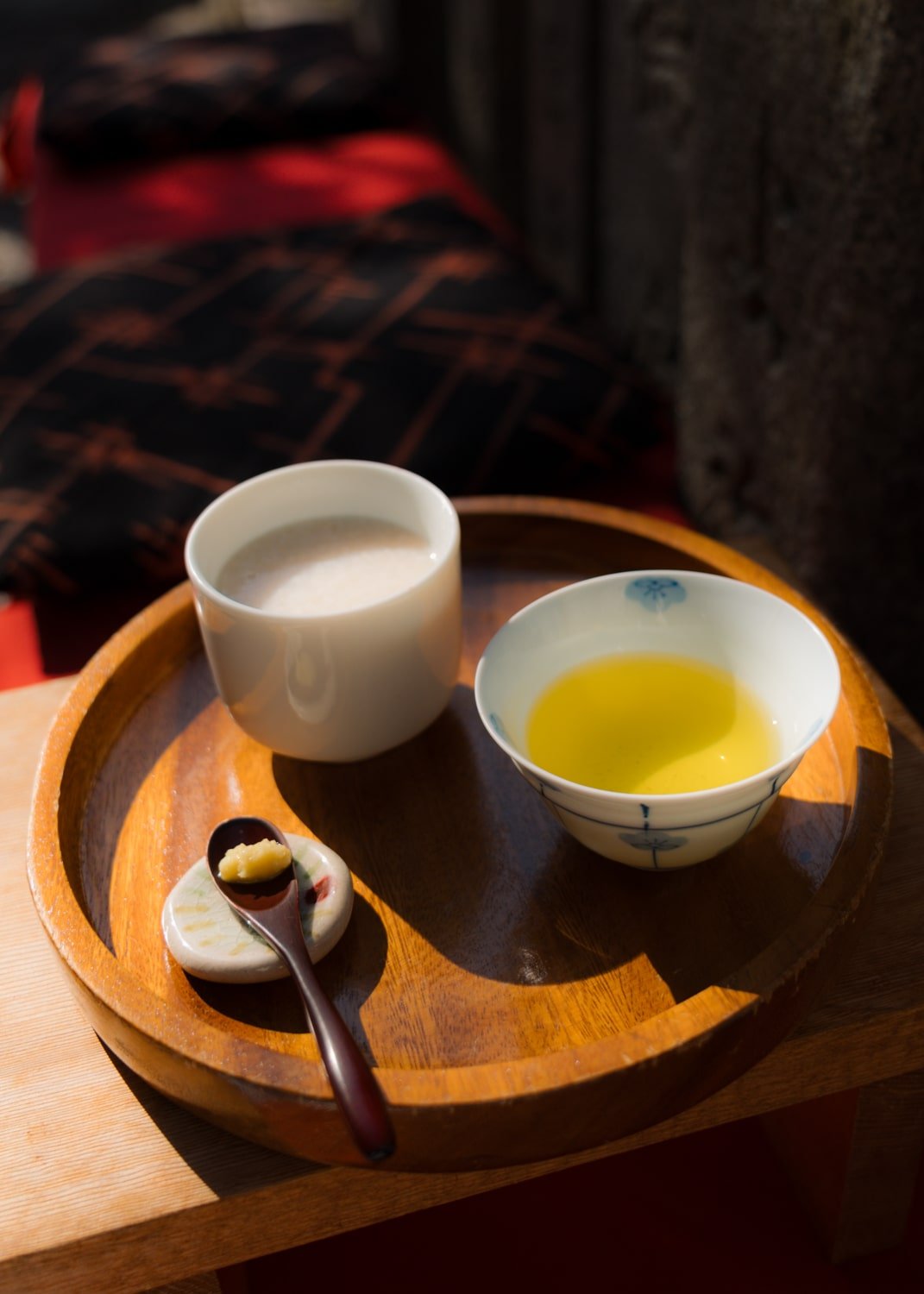 Amazake and green tea with a spoon of minced ginger, on a round wooden platter at Fushimi Inari Shrine in Kyoto, Japan.