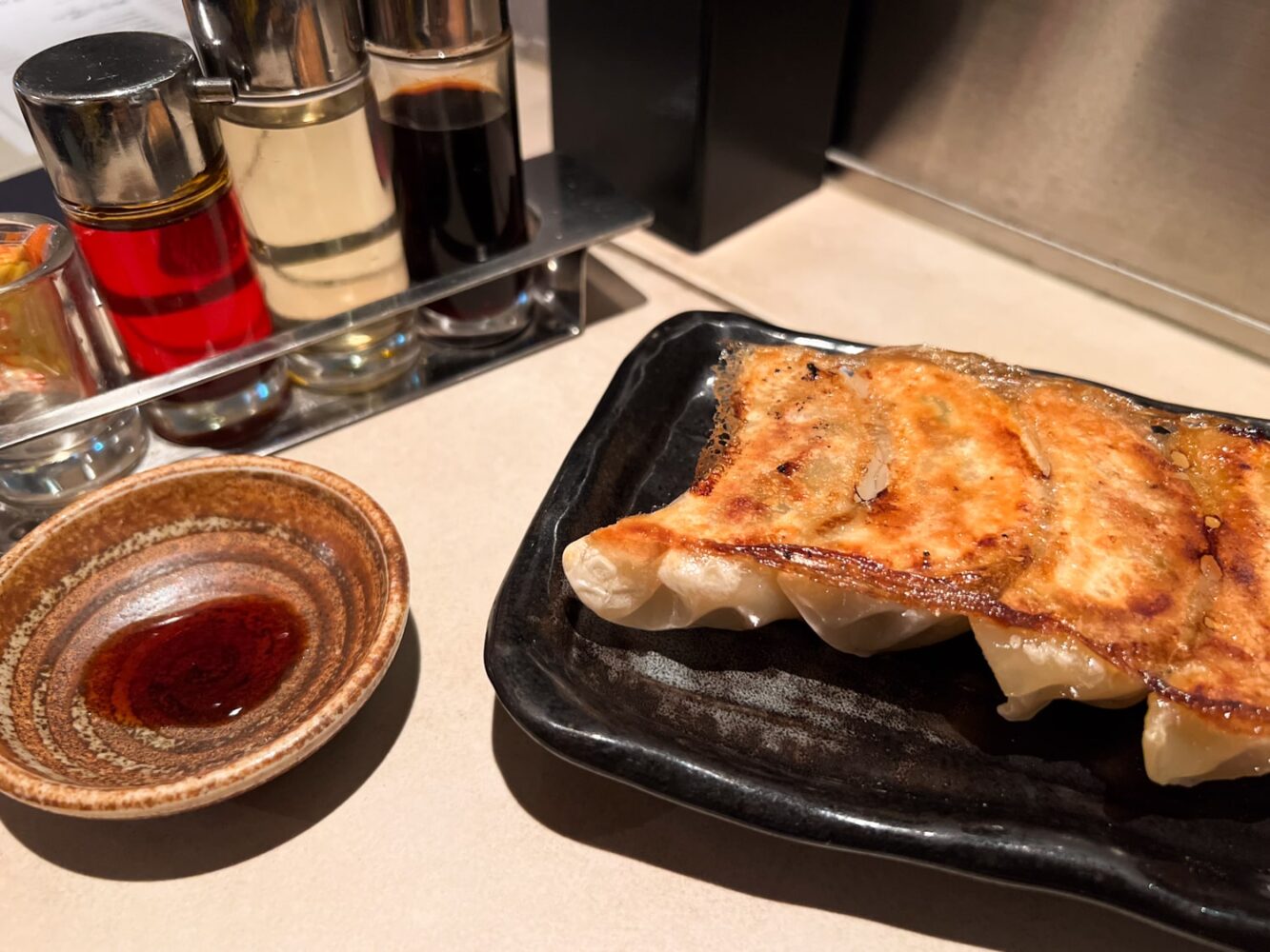 Plate of Japanese gyoza (potstickers) with dipping sauce at an izakaya restaurant.