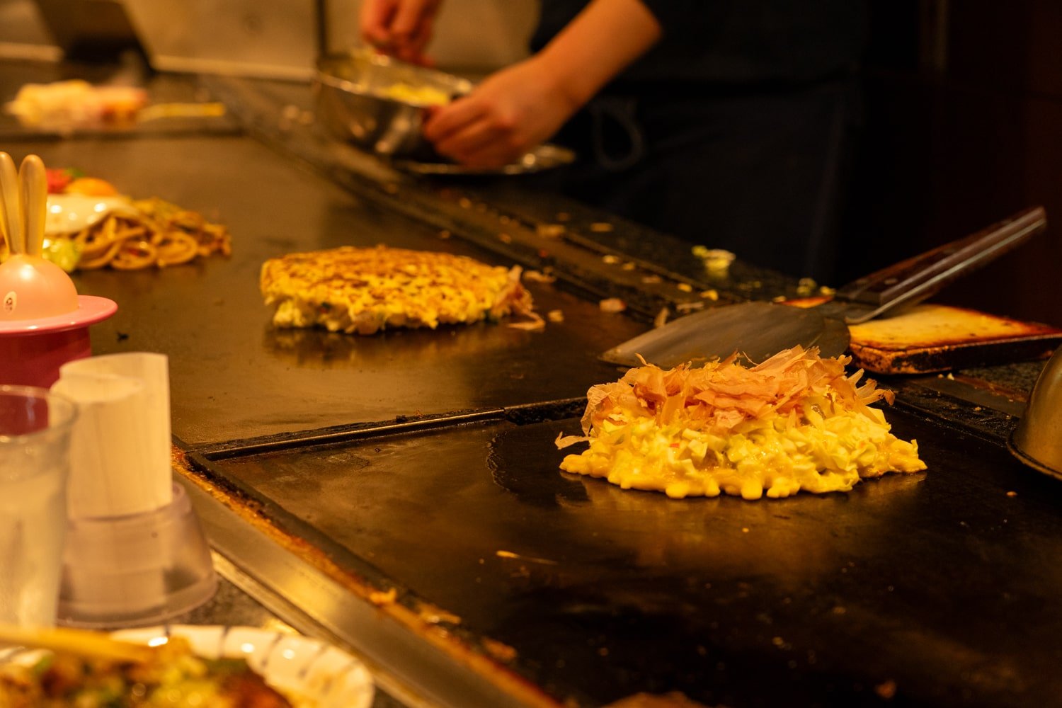 Japanese Osaka-style okonomiyaki on a grill (teppan).