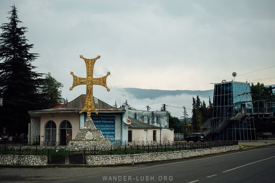 A hazy morning in Martvili, Georgia, with a cable car station and a big golden cross on the side of the road.